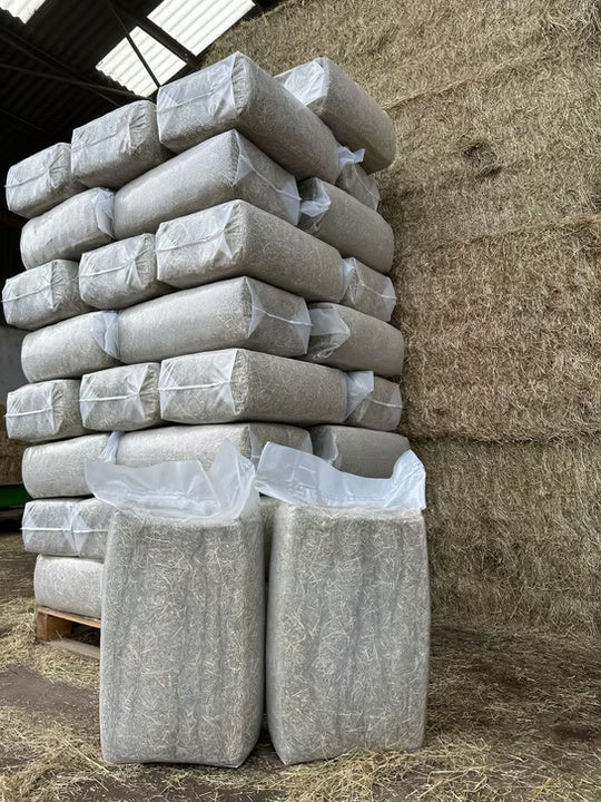 Stack of wrapped bales of hay in a barn setting